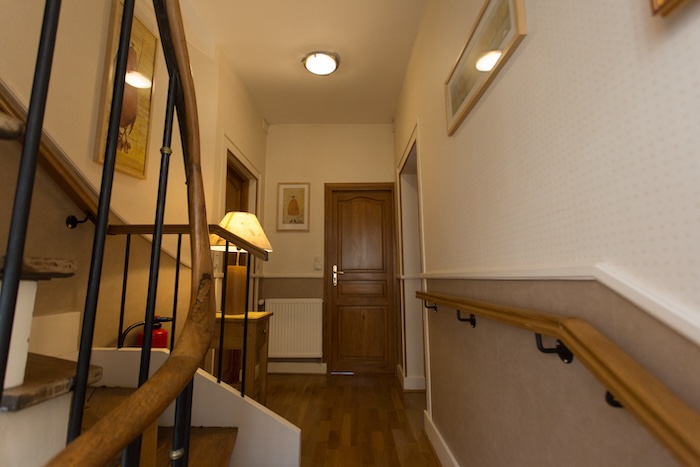 Une vue du palier dans les escaliers anciens et au fond la porte d’une des chambres de Linterfaces.