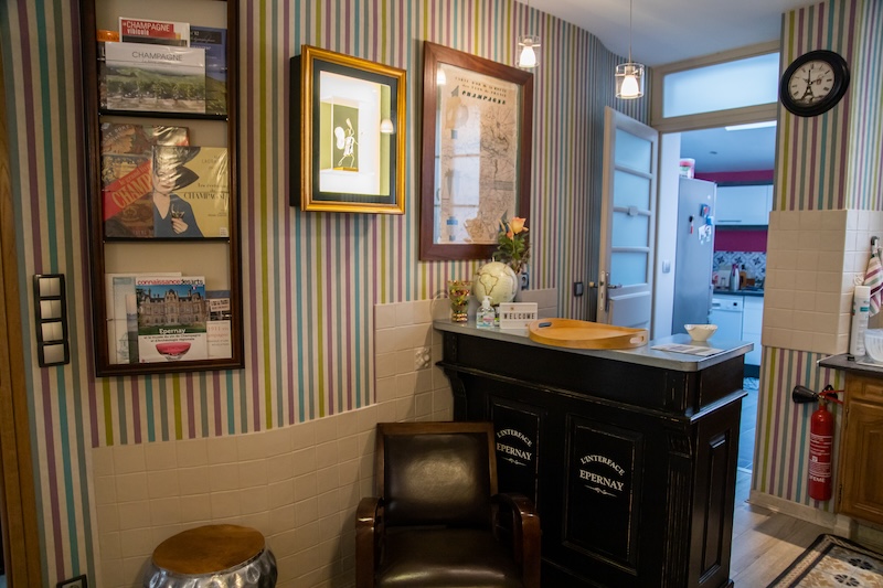 On voit le bar vintage noir dans la salle à manger de Linterfaces, au mur, plusieurs cadres et revues anciennes.