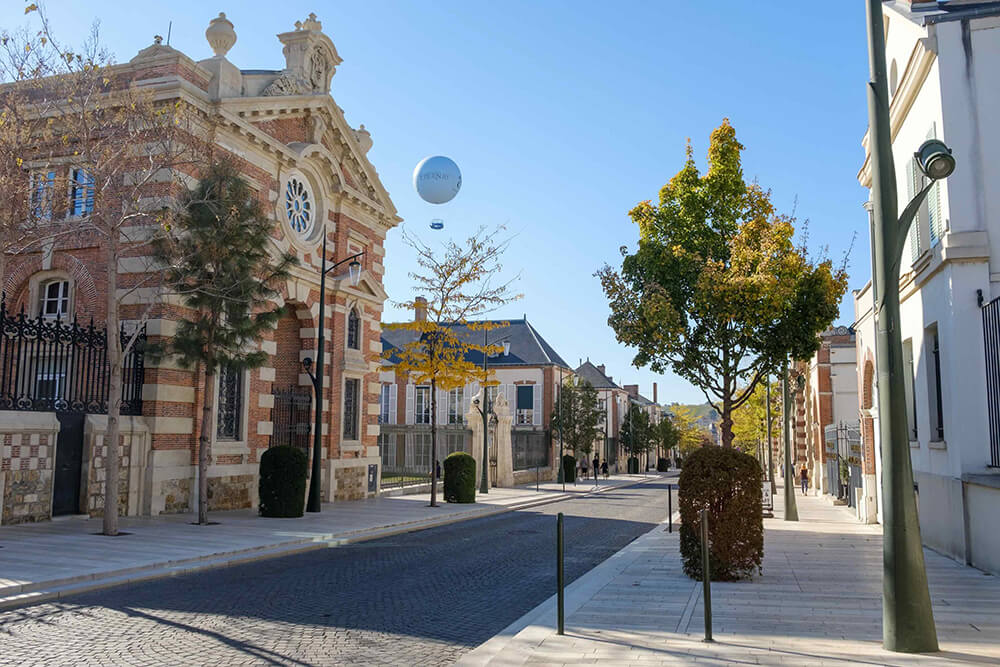 On voit une partie de l’avenue de Champagne d’Épernay avec le ballon captif dans le ciel au loin derrière les bâtiments