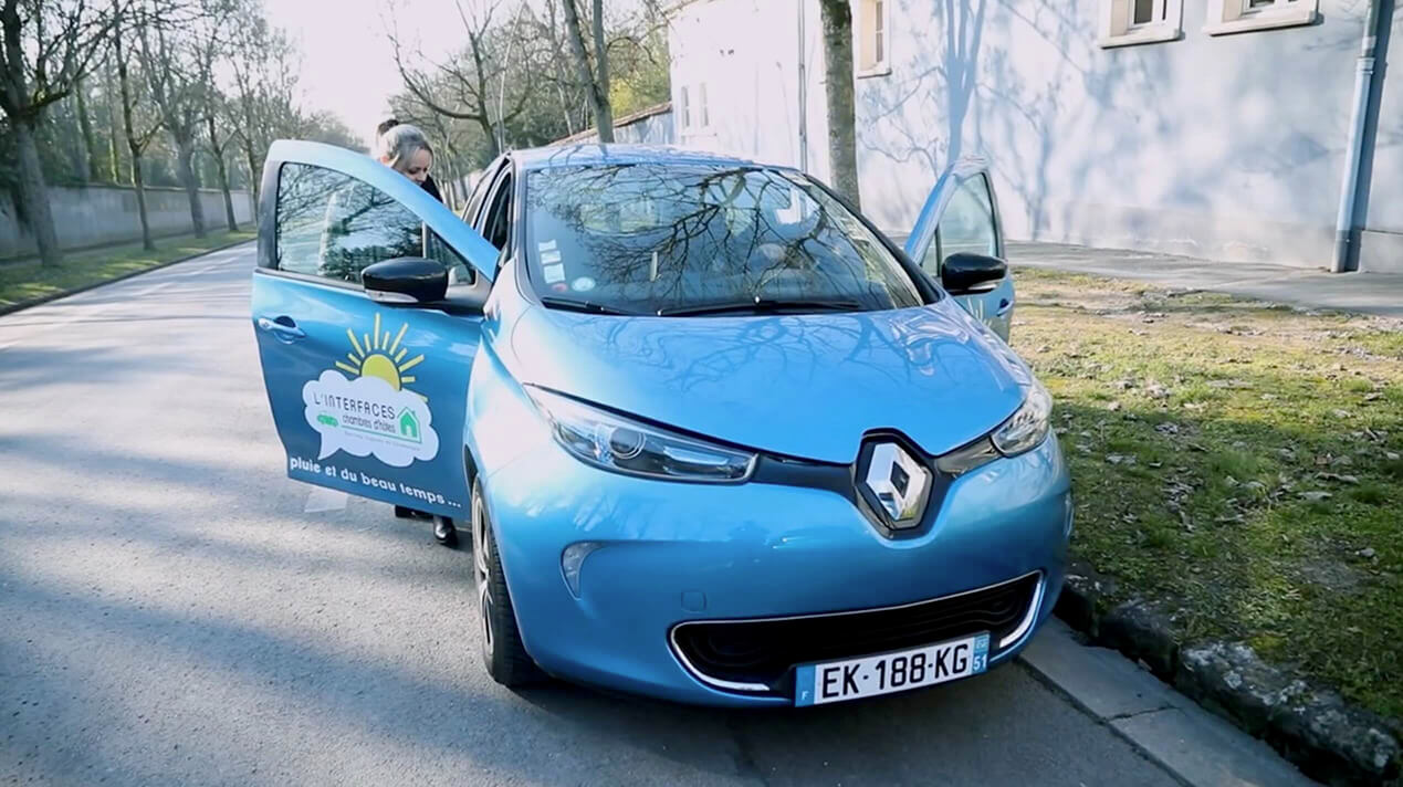 On voit 2 visiteurs de Linterfaces entrant dans une des voitures électriques lors de leur découverte de la région