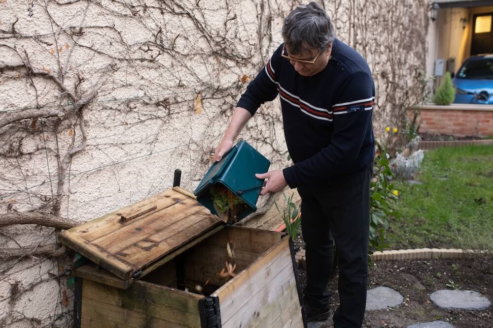 On voit Didier jetant les bio déchets dans le composteur présent dans le jardin de Linterfaces